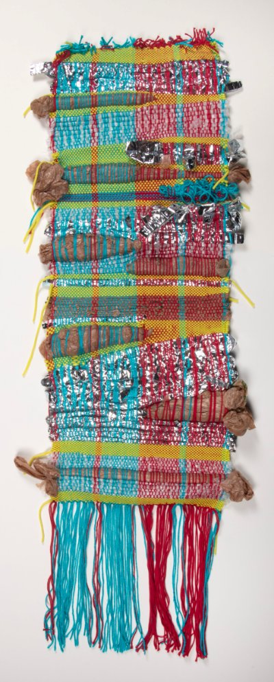 A wall weaving made up of yarn, plastic bags, and other trash. The main colors are red, turquoise, yellow, brown, and silver.